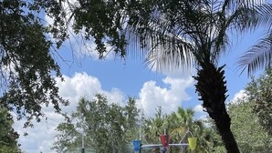 A water play area with slides and climbing structures, surrounded by trees and a clear sky. - Platinum rated 2BR ground floor next to pool big screen TVs, Huge patio, wifi (Davenport)