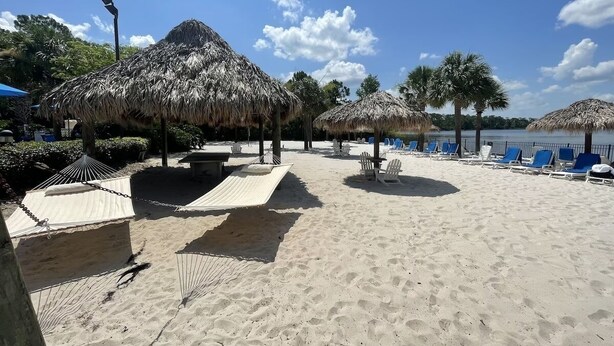 A beach with thatched umbrellas, lounge chairs, and a sandy area. - Platinum rated 2BR ground floor next to pool big screen TVs, Huge patio, wifi (Davenport)