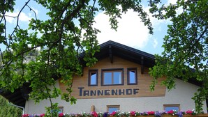 A building with the name "Tannenhof" on the facade, surrounded by lush greenery. - Beautiful Family Apartment (Hinterbichl)