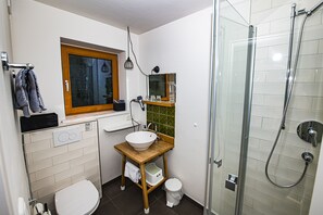 A compact bathroom with a toilet, sink, and shower.
