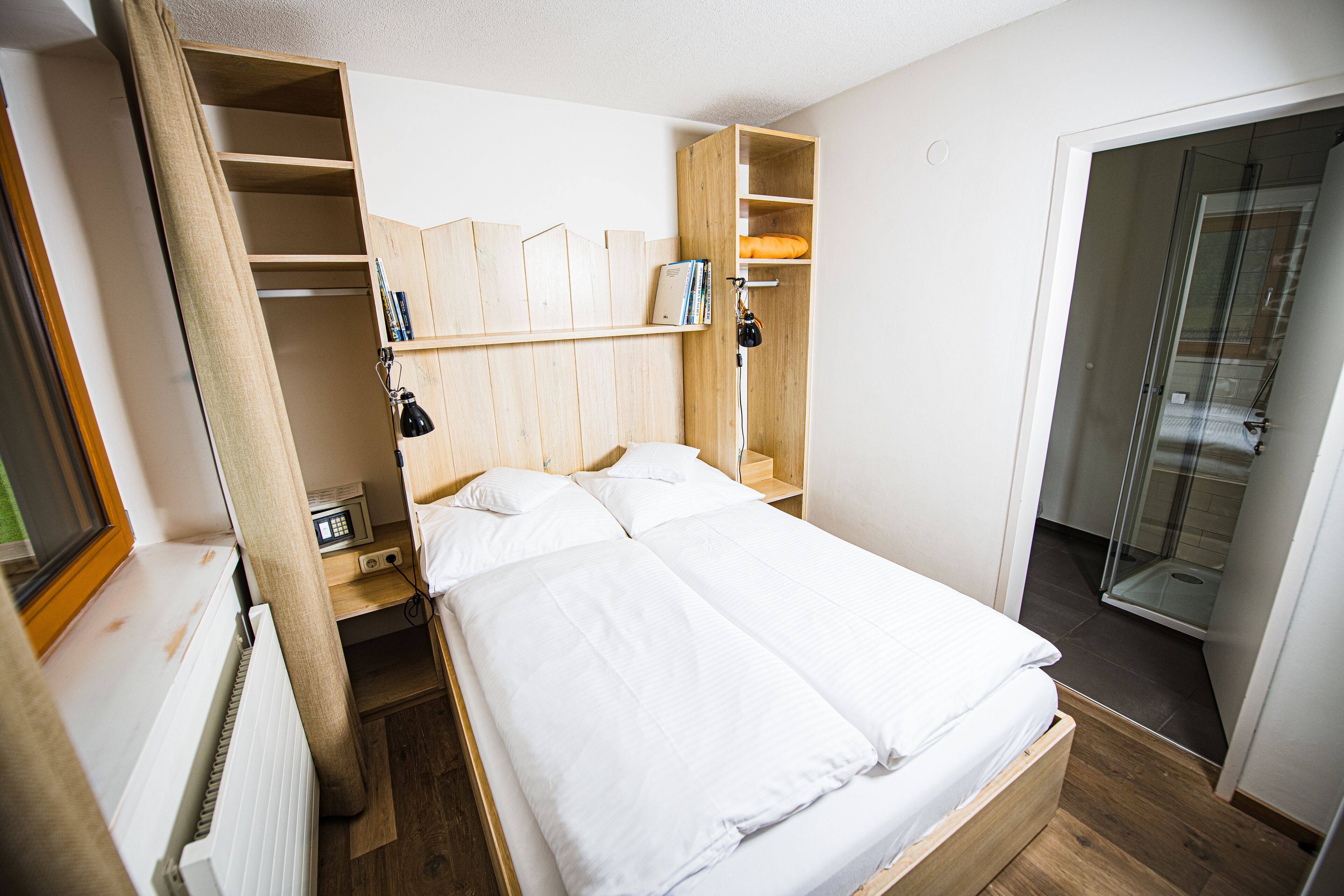 Ein Schlafzimmer mit einem Bett, einem Holzschrank und einem Badezimmer mit Dusche.