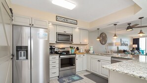 A modern kitchen with stainless steel appliances, white cabinetry, and a granite countertop.