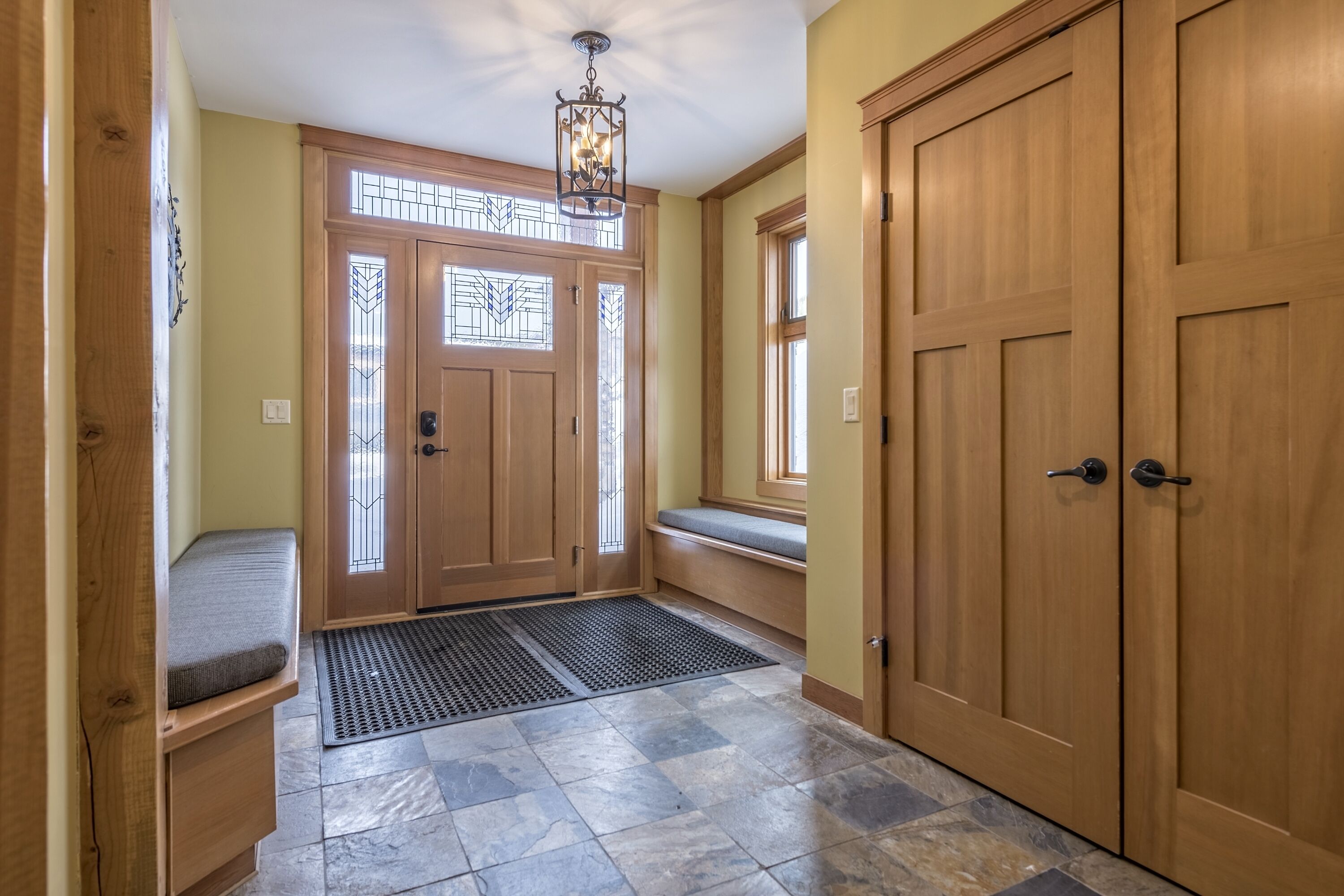 A hallway with a wooden door, a bench, and a window.