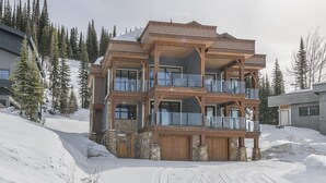 A multi-story wooden building with balconies, set in a snowy landscape with trees.