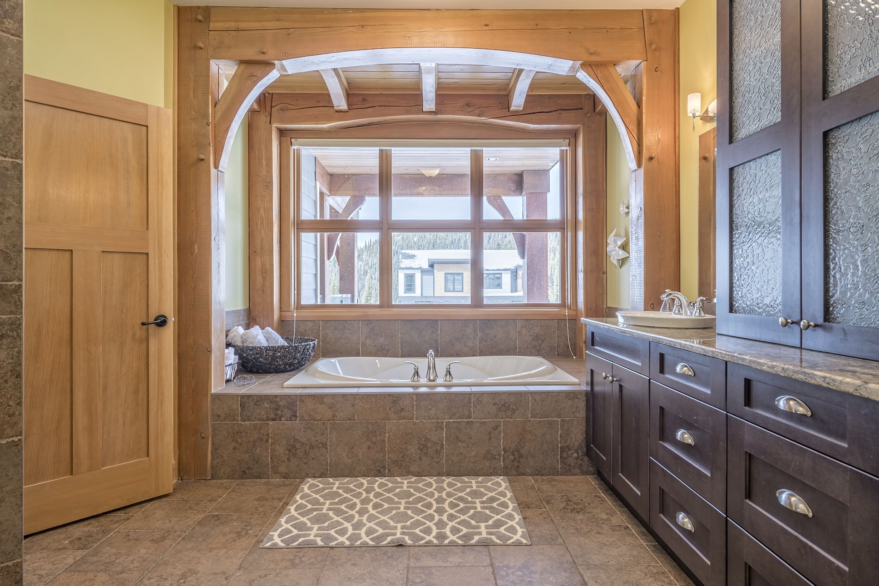Un bagno con un'ampia finestra, una vasca da bagno e mobili in legno scuro.