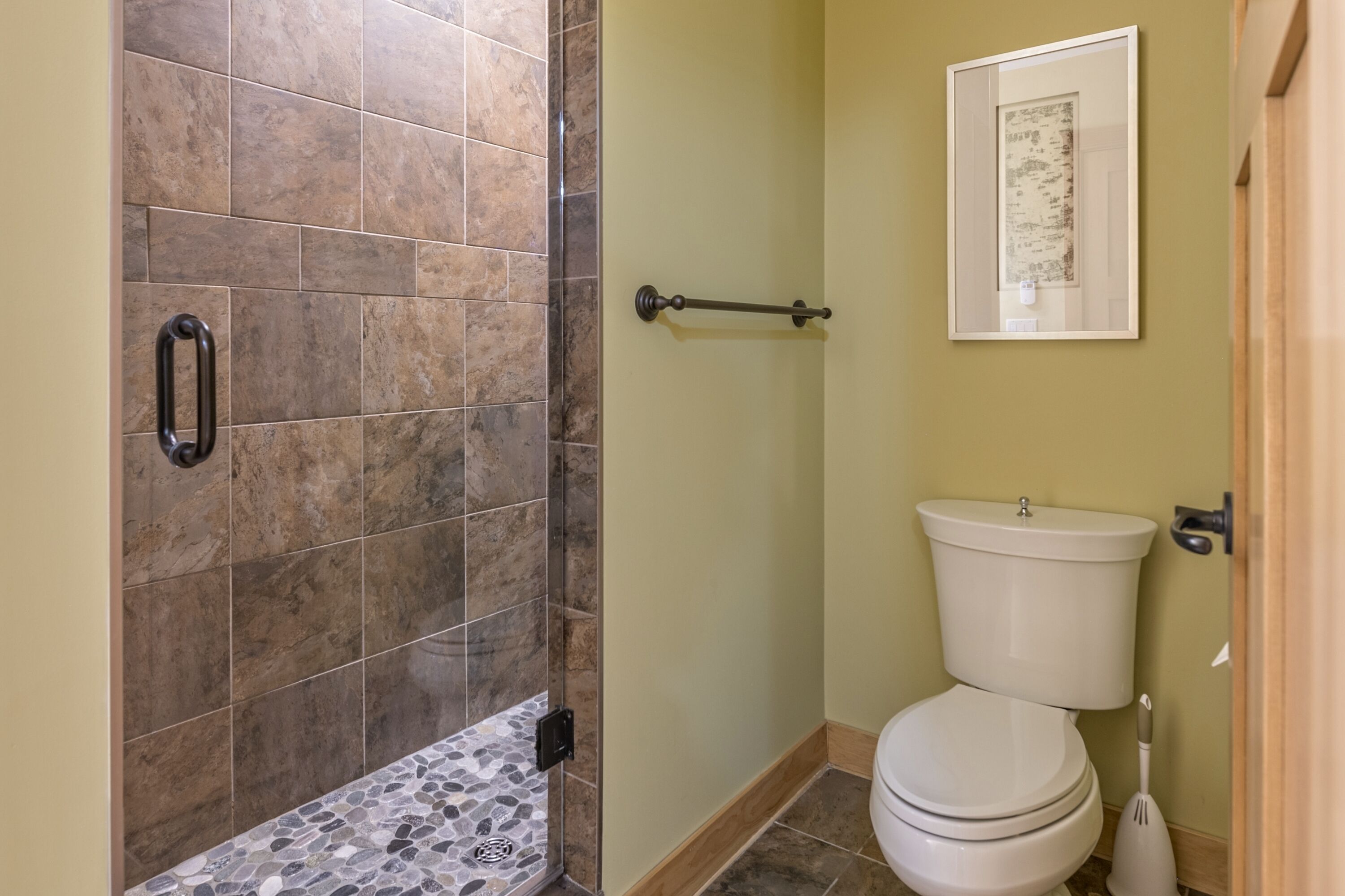 A bathroom with a shower area, a toilet, and a towel rack.