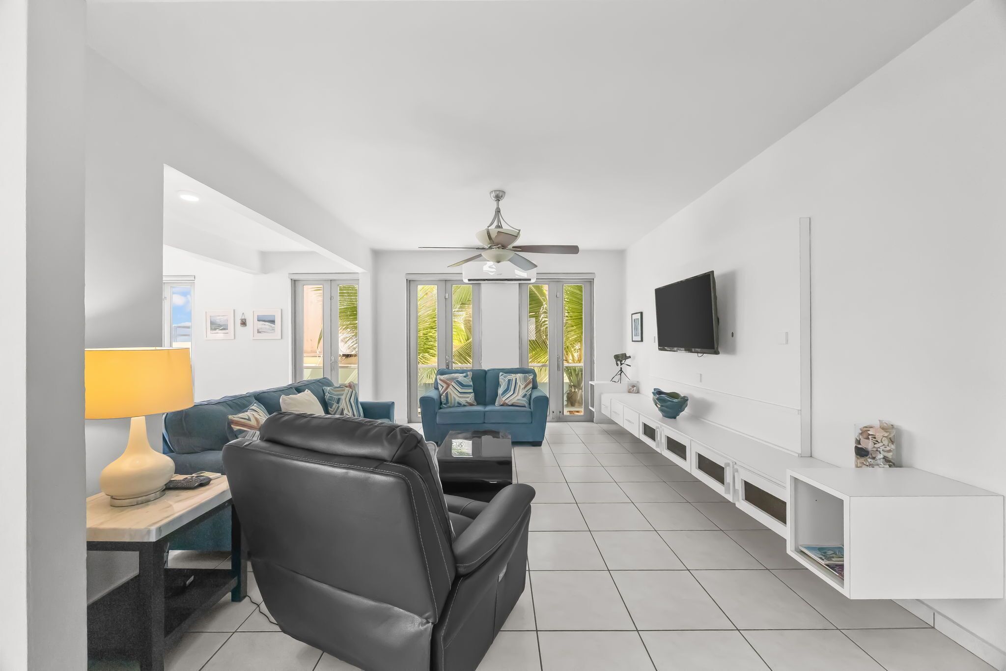 A modern living room with a sofa, a chair, a TV, and a ceiling fan.
