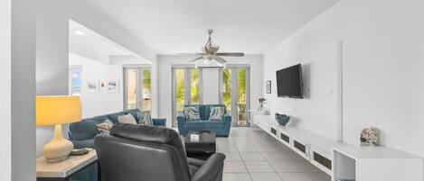 A modern living room with a sofa, a chair, a TV, and a ceiling fan.