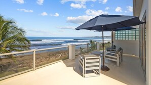 Een balkon met uitzicht op zee, een tafel met stoelen en een parasol.