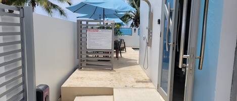 A gated entrance to a building with a blue umbrella and a signboard.