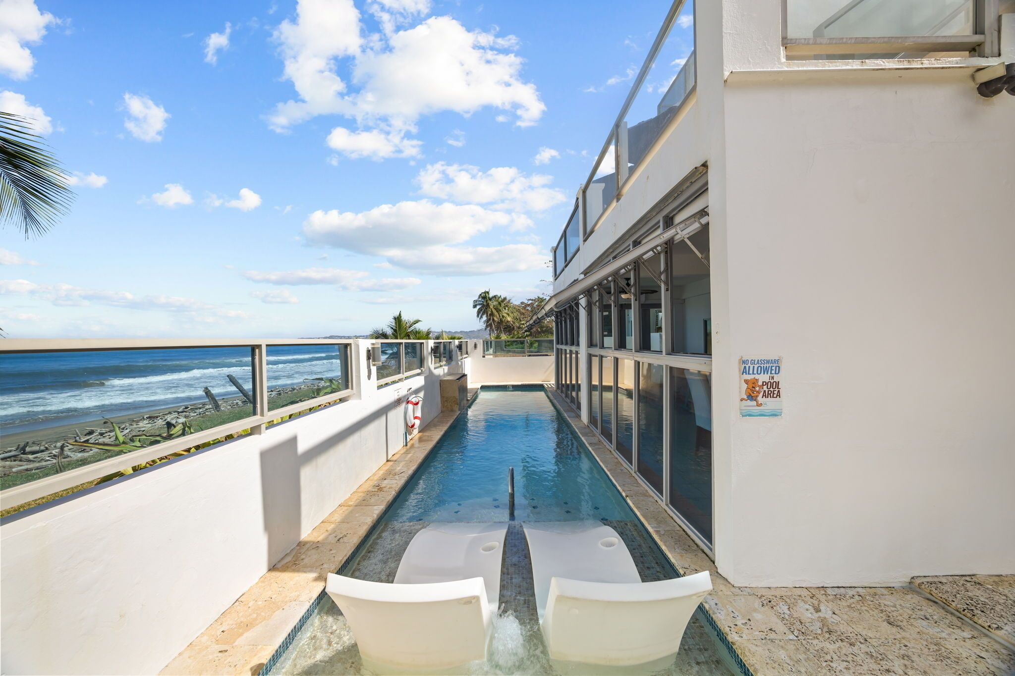 A pool area with a view of the ocean, a lifeguard stand, and a sign indicating no diving allowed.