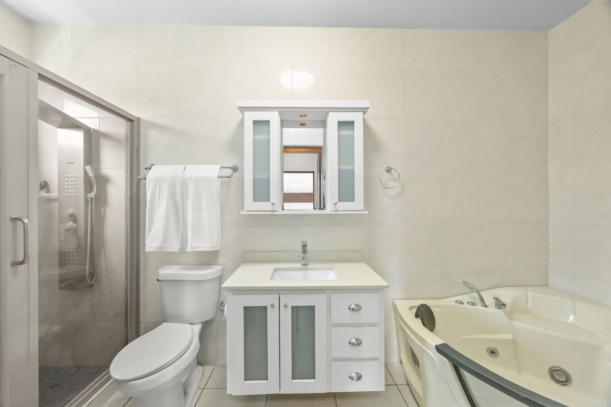 Une salle de bain moderne avec une douche à parois de verre, des toilettes, un lavabo avec un meuble-vasque et une baignoire.