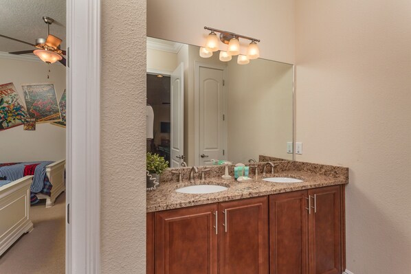 A bathroom with two sinks, a large mirror, and a ceiling fan.