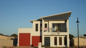 A modern two-story building with a red garage door, a balcony, and a sign that reads "Bunker Cove." - Bunker Vista at Dunes Golf Links (Port Hughes)