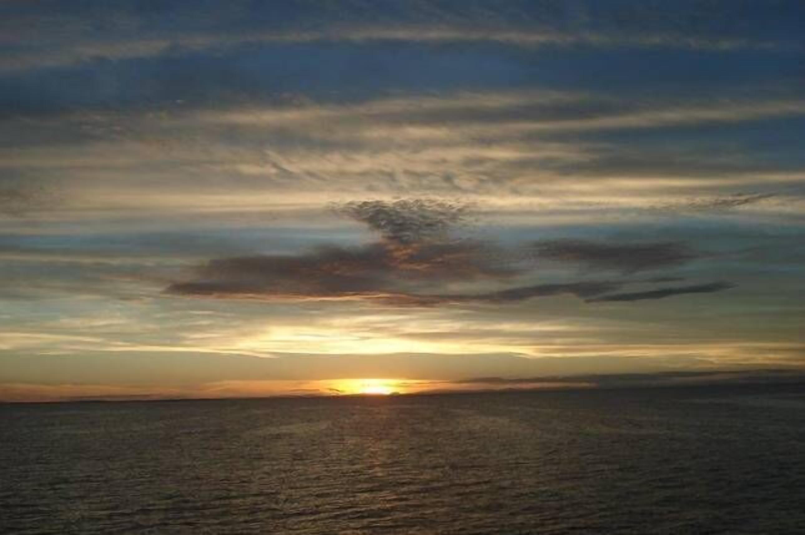 A sunset over a calm sea with a clear horizon.