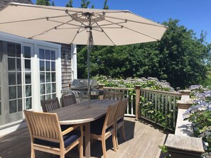 Une terrasse en bois avec une table et des chaises, un parasol et un barbecue.