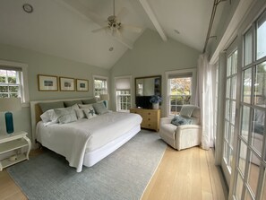 Une chambre à coucher avec un grand lit, une commode, une chaise et un ventilateur de plafond.
