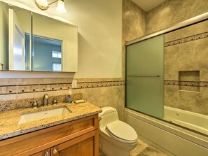 A bathroom with a granite countertop sink, a toilet, a glass shower enclosure, and a mirror above the sink. - Direct Beach Access and Expansive Atlantic Ocean Views! (North Wildwood)