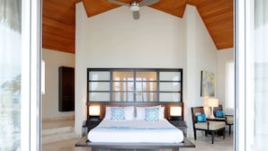 A spacious bedroom with a large bed, a ceiling fan, and a view of the outdoors.