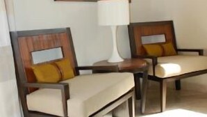 Two dark wooden chairs with light-colored cushions and a white table between them.