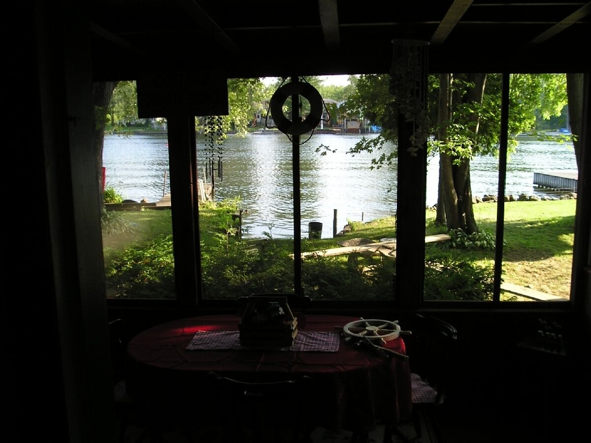 Una stanza con un'ampia finestra vista lago, un tavolo con tovaglietta e un salvagente appeso alla finestra.