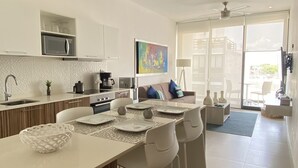 Een moderne keuken met een centraal eiland, witte kasten en een eethoek met een tafel en stoelen.