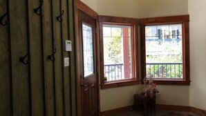 Een hoekappartement met een houten deur, twee ramen met uitzicht op een balkon en een thermostaat aan de muur.