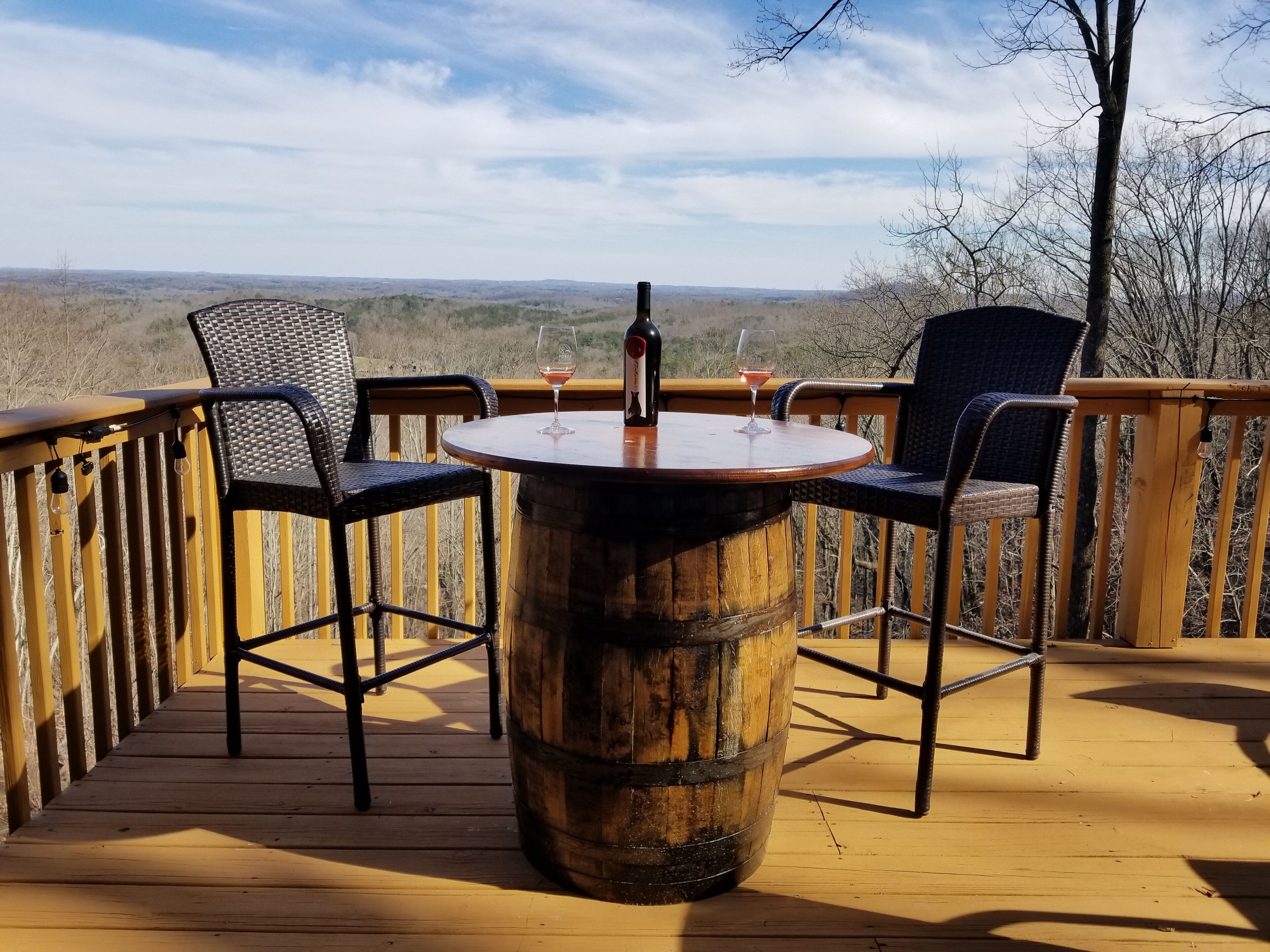Une terrasse en bois avec une table ronde et deux chaises, offrant une vue sur un paysage magnifique.