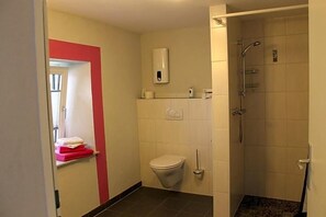 Une salle de bain équipée de toilettes, d’une douche et d’un sèche-mains.
