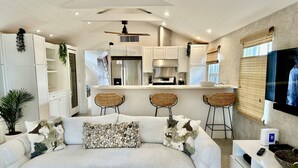 Una sala moderna con sofá, mesa de centro y una cocina con taburetes de bar.