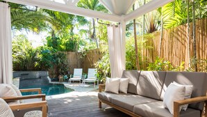 Un espacio al aire libre techado con piscina, terraza de madera y asientos.