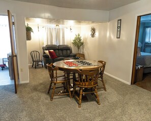 A dining area with a round wooden table and chairs, a grey sofa with a red pillow, and a plant. - Country Farmhouse, family friendly, beautiful views, gorgeous sunsets (Thomas)