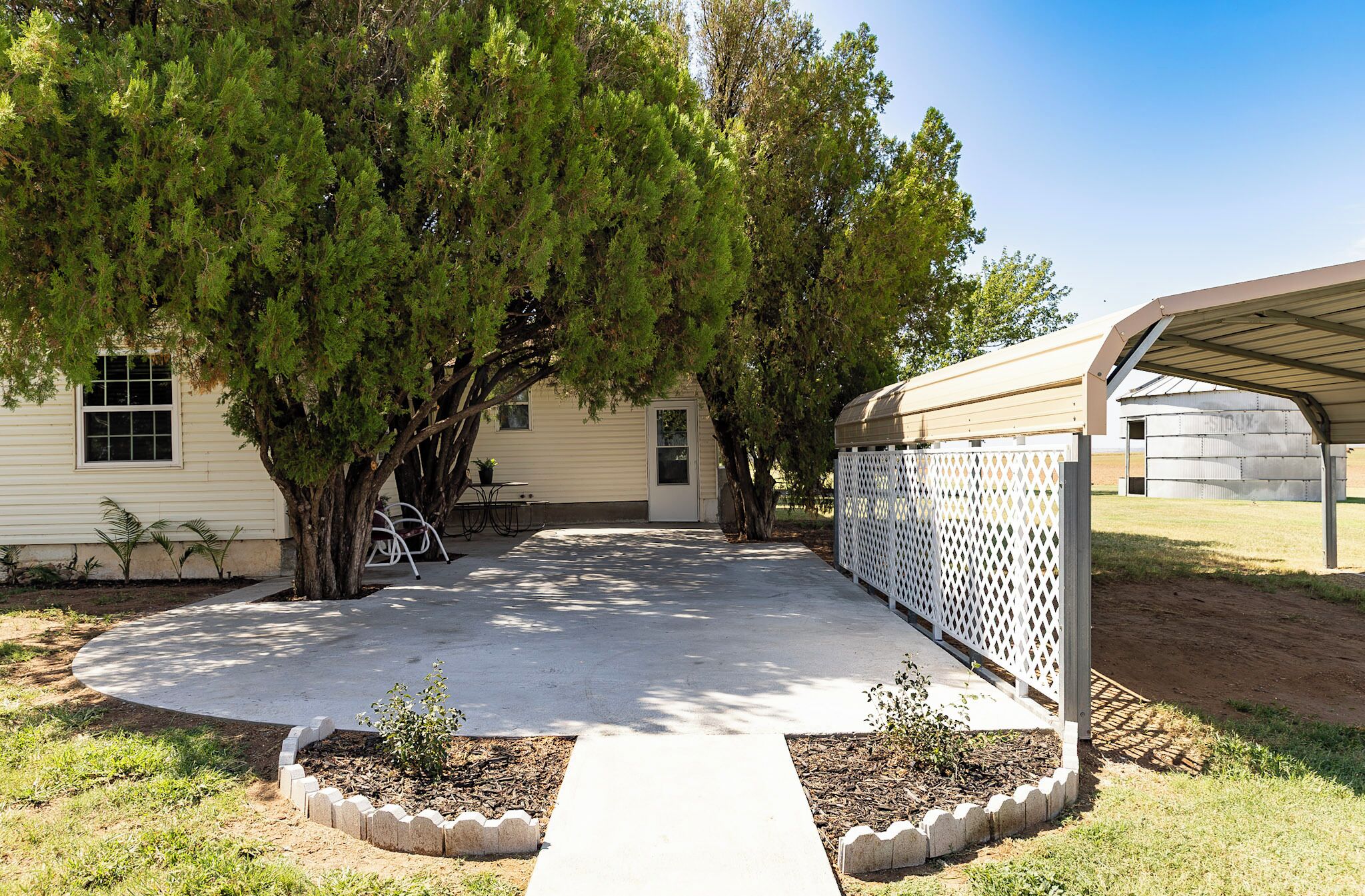A residential property with a covered patio, a fenced yard, and a house with a window and door.