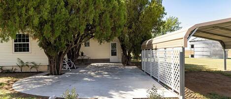A residential property with a covered patio, a fenced yard, and a house with a window and door.