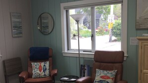Una habitación con dos sillones de cuero, una mesita, un sofá y una ventana con vistas a la calle.
