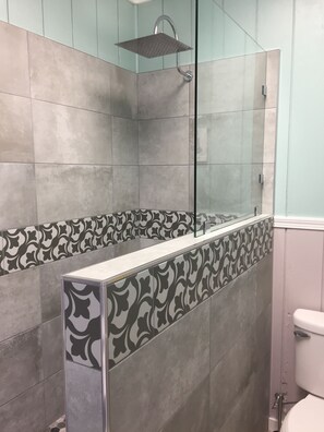 Ein modernes Badezimmer mit Dusche, Fliesenwänden und einem dekorativen Fliesenstreifen.