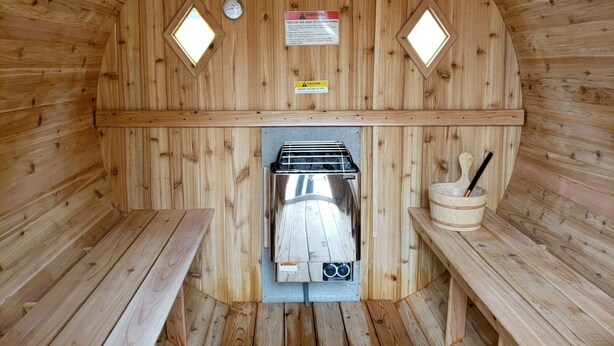 A sauna with wooden walls, a central heater, two benches, and warning signs. - Lake Superior Home - Perfect for a family vacation any time of the year! (Calumet)