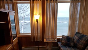 A cozy room with a view of the ocean, a wooden cabinet, a sofa, and a lamp. - Lake Superior Home - Perfect for a family vacation any time of the year! (Calumet)