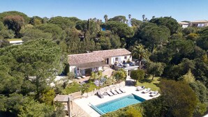 A villa with a swimming pool, surrounded by dense trees and a hilly landscape. - Contemporary villa 500 m beach and club 55 (Ramatuelle)