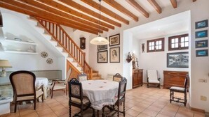 Ampla sala de estar com mesa de jantar, cadeiras, escada e uma grande janela.