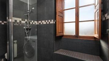 Een bad/douchecombinatie, een haardroger, handdoeken, toiletpapier