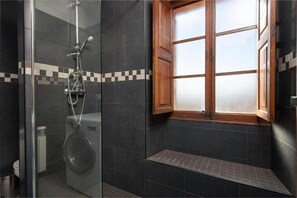 Een bad/douchecombinatie, een haardroger, handdoeken, toiletpapier