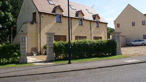 Un bâtiment à deux étages, doté d’un toit en pente, de nombreuses fenêtres et d’une voiture garée dans l’allée.