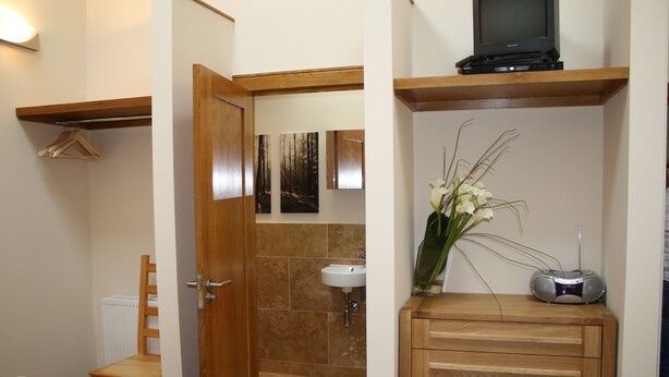 Une salle de bain avec un meuble en bois, un lavabo et un espace douche.