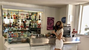 A bar area with a variety of liquor bottles and glasses, a sink, and a countertop.