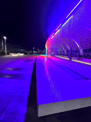 A modern architectural structure with a curved design and illuminated water features. - Hotel Napoleon (Riccione)