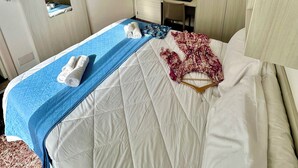 A hotel room with a bed, a desk, a wardrobe, and an air conditioning unit.