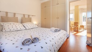 A bedroom with a bed, pillows, a wardrobe, and a chair. - Spacious and bright designer apartment next to Playa Larga (Tarragona)