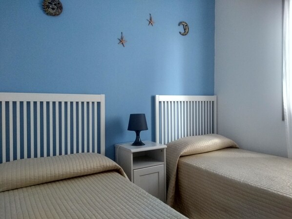 Une chambre avec deux lits, une table de chevet et une lampe.