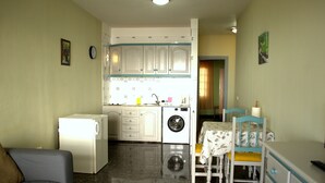 A compact living space with a kitchenette, a washing machine, a dining table with chairs, and a sofa. - Casa Junonia Apartments, with terrace, Bajo C (Playa de Santiago)